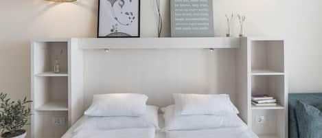 A modern bedroom with two single beds, a large framed artwork, a motivational quote, and built-in shelving.