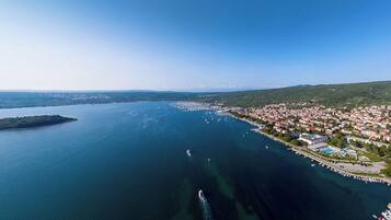 An aerial view of a coastal town with a marina, houses, and a clear sky.