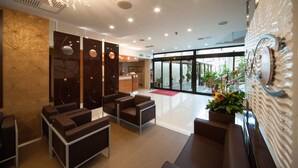 A modern lobby with seating areas, a reception desk, and a large glass door leading outside. - Magris Hotel (Naples)