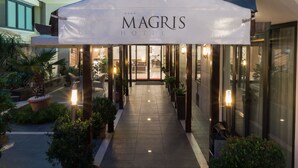 The exterior of the Magris Hotel with a covered entrance, potted plants, and a well-lit pathway leading to the entrance. - Magris Hotel (Naples)