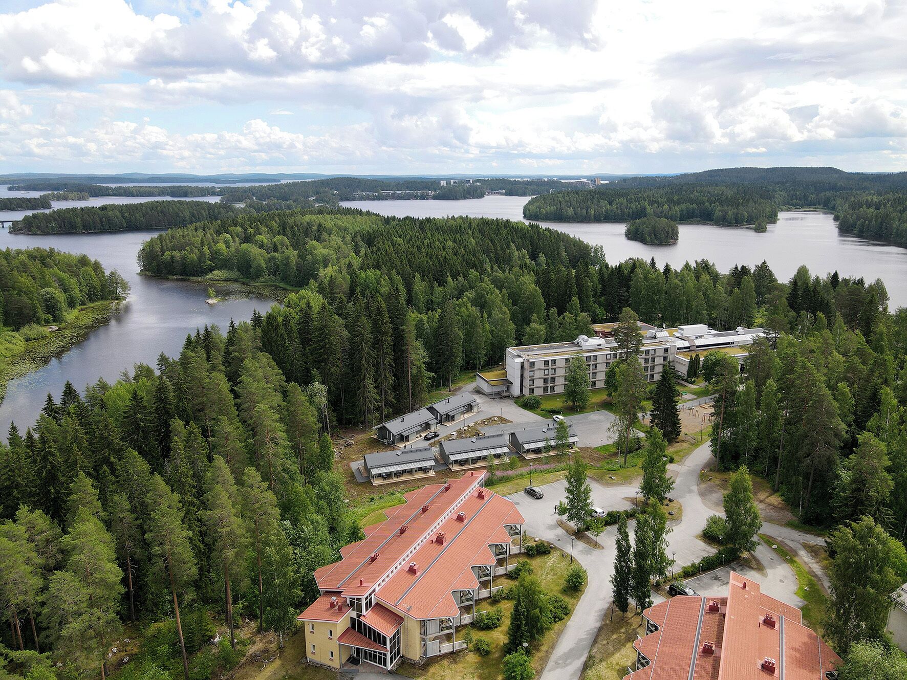 A large building complex surrounded by dense forest and lakes.