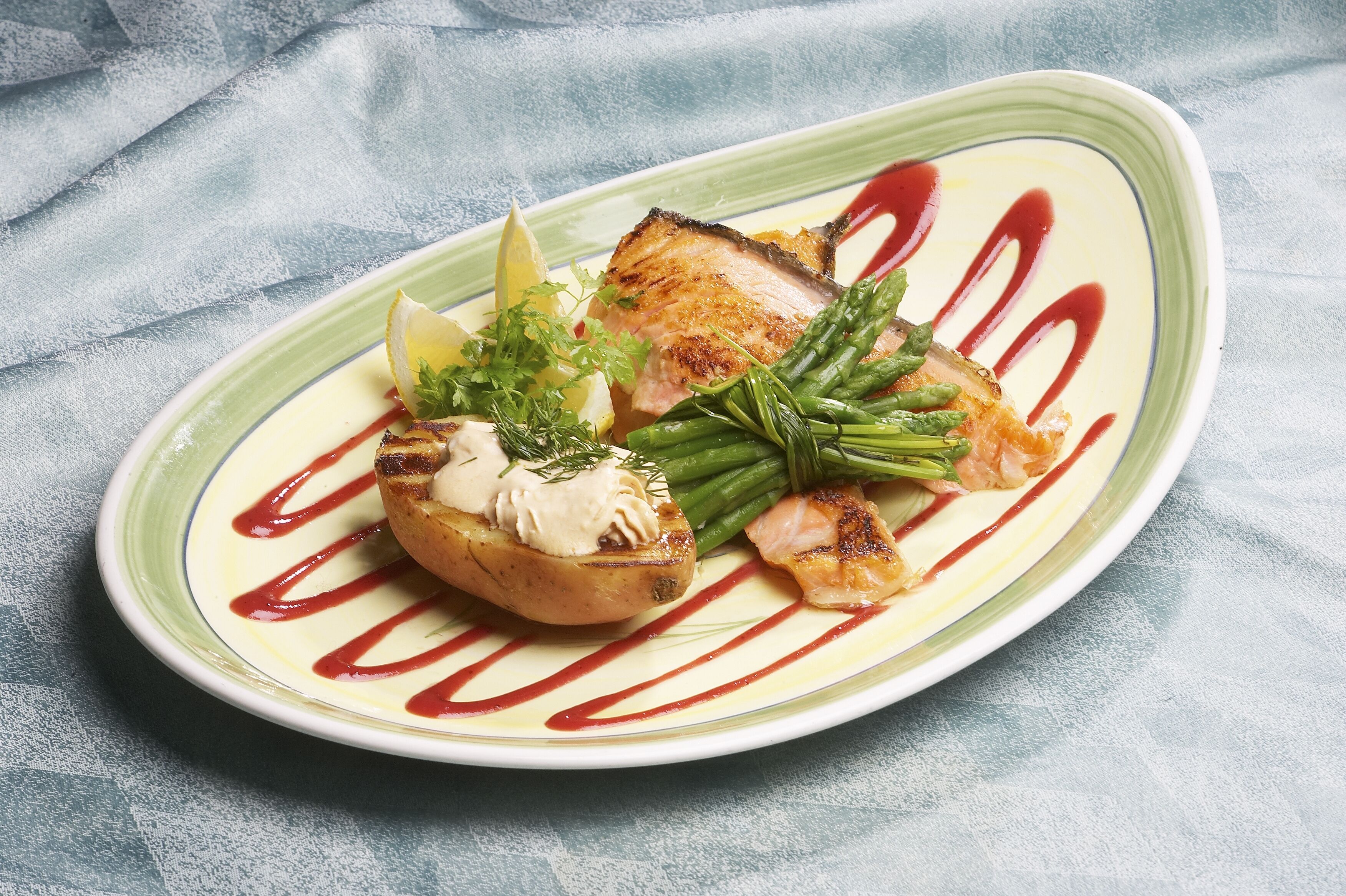 Une assiette de nourriture comprenant de la viande grillée, des légumes et une sauce.