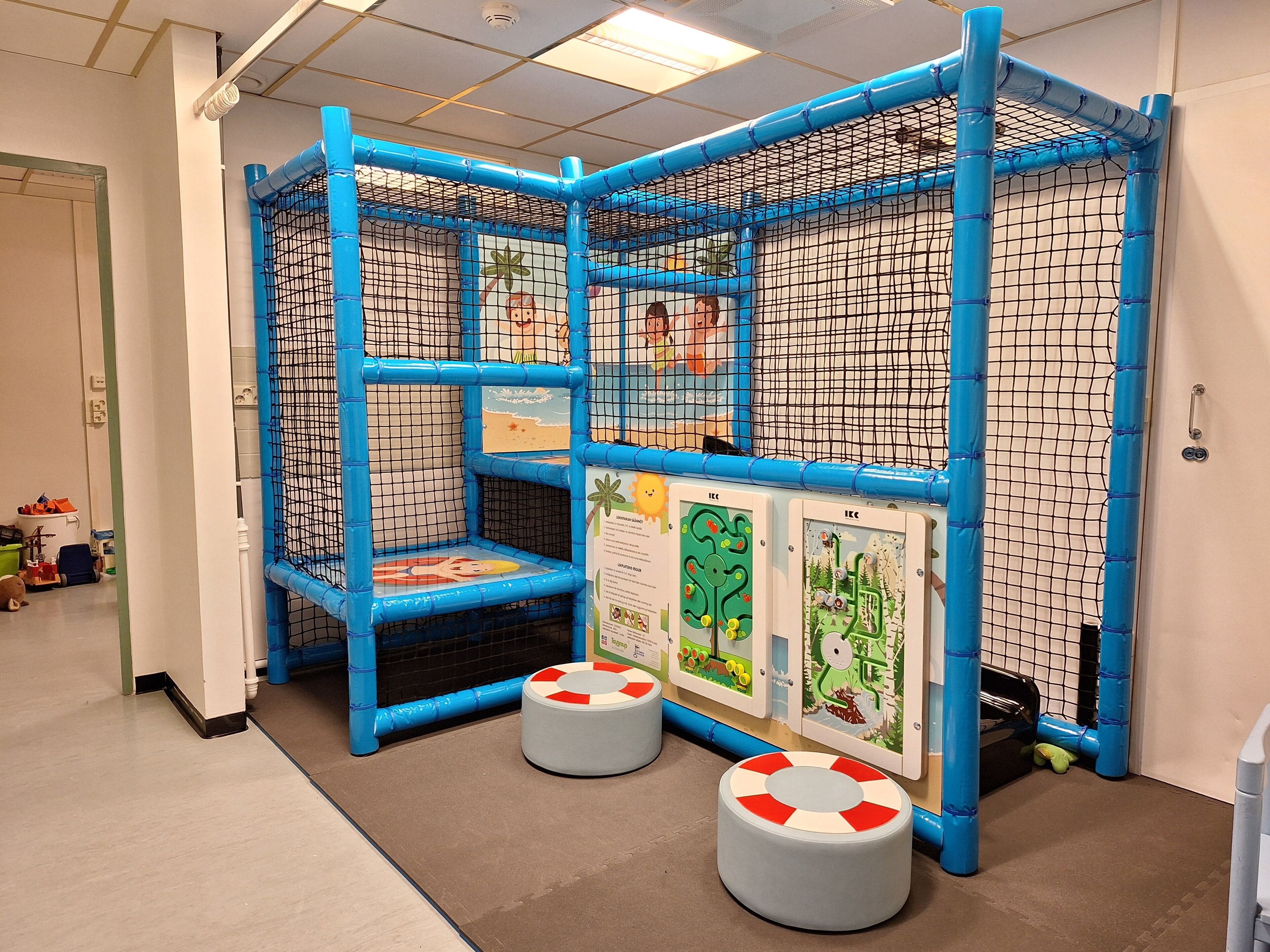 A play area with a blue play structure, a small table, and two stools.