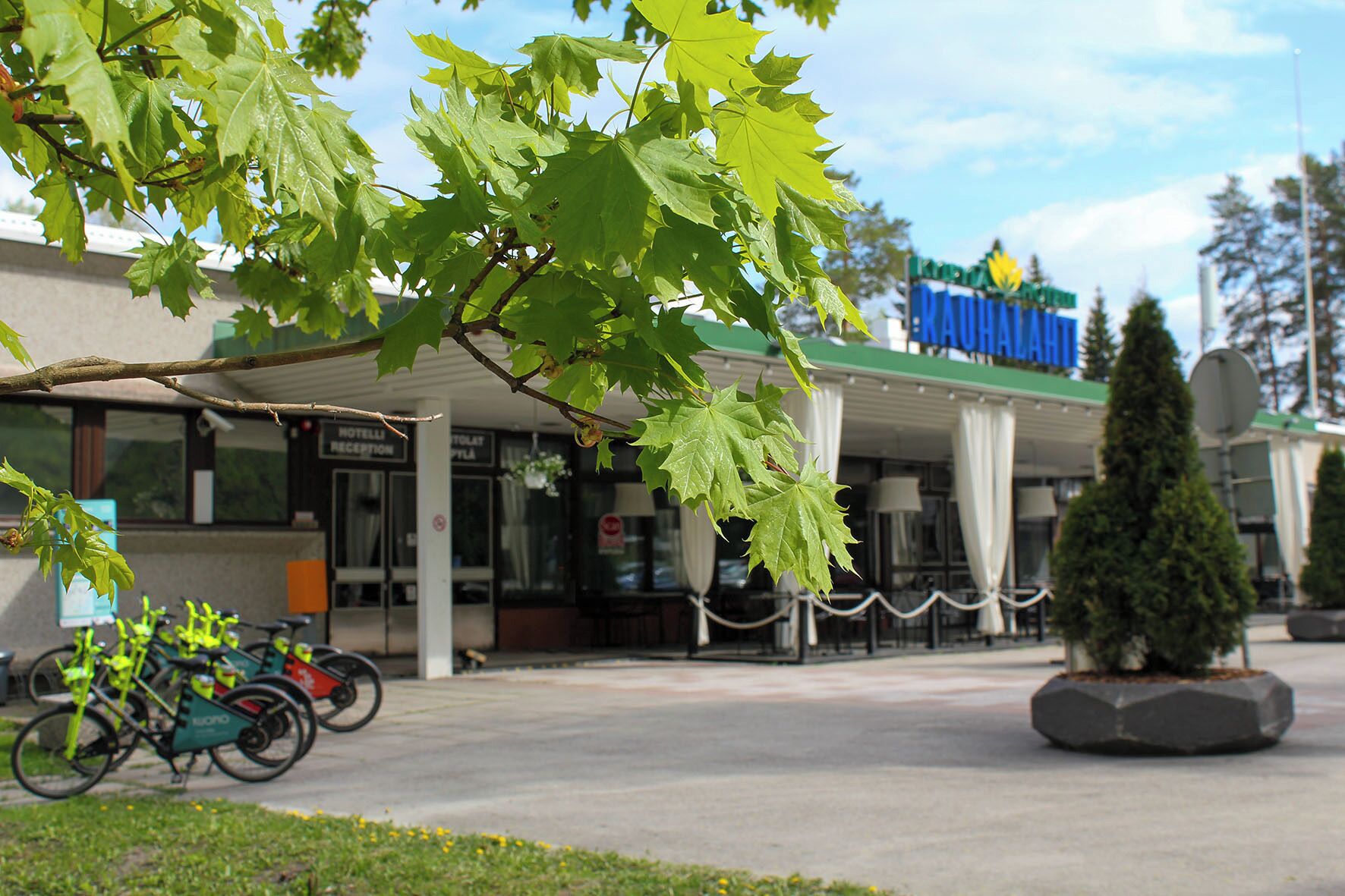 A hotel with a reception area, a parking lot with bicycles, and a sign for 'HOTEL'.
