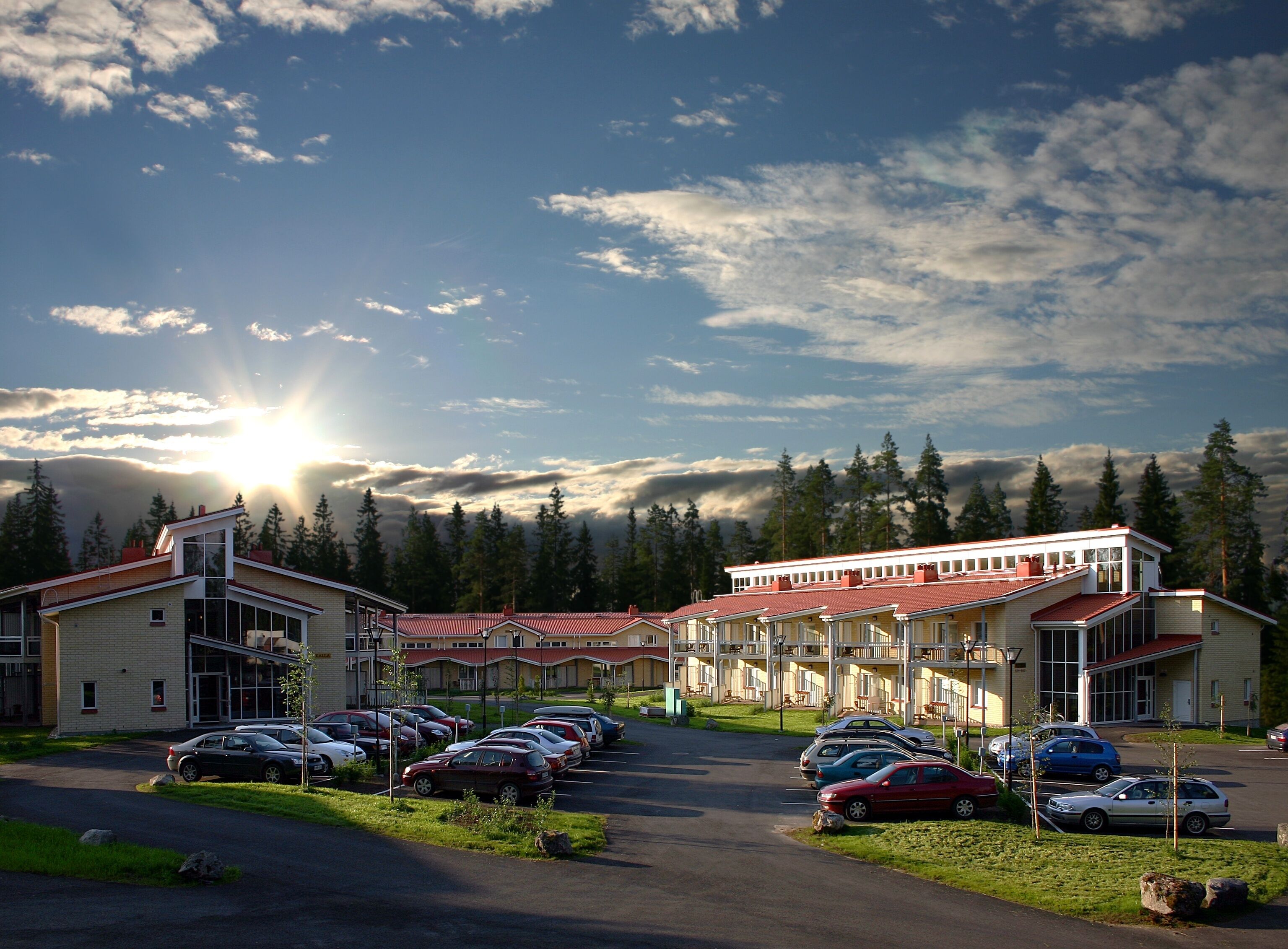 A hotel with a parking lot and a view of the surrounding forest.