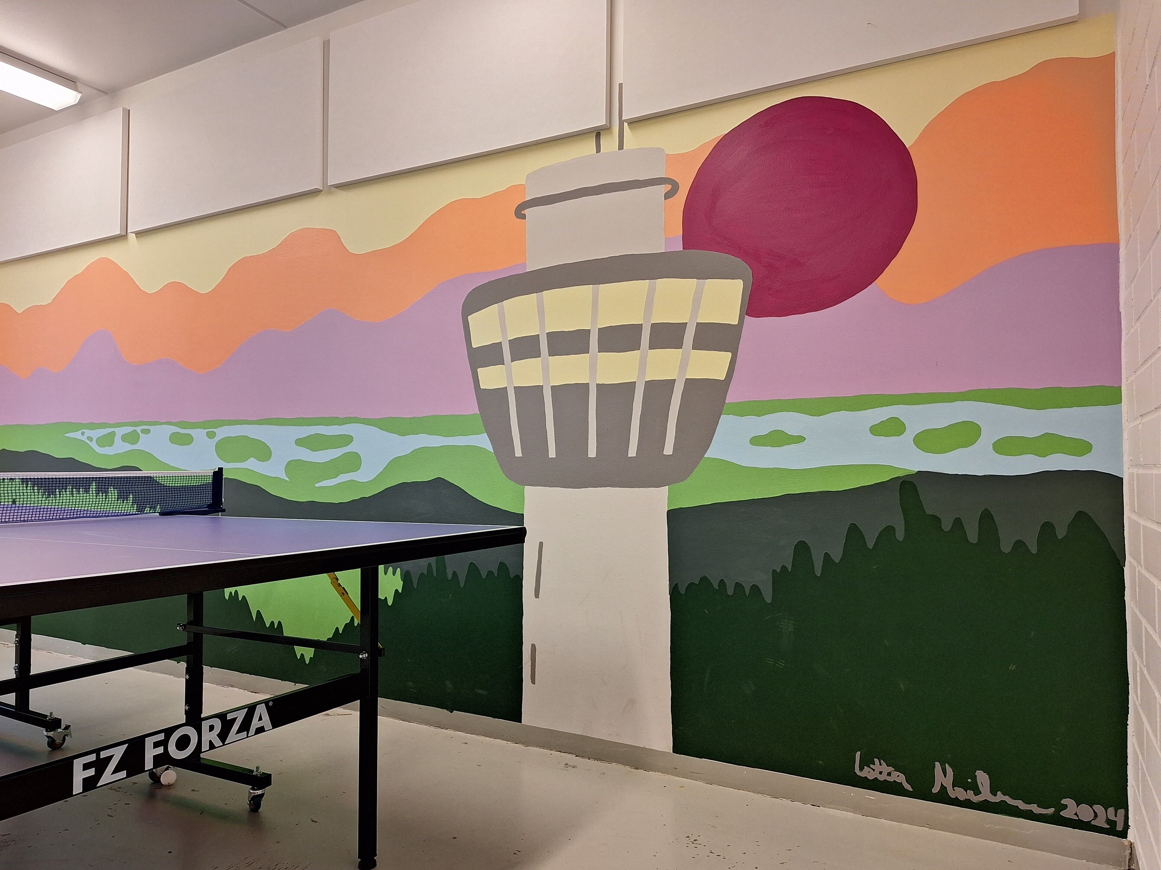A ping pong table with "FZ FORZA" branding, a mural with a sunset and landscape, and a signature at the bottom right.