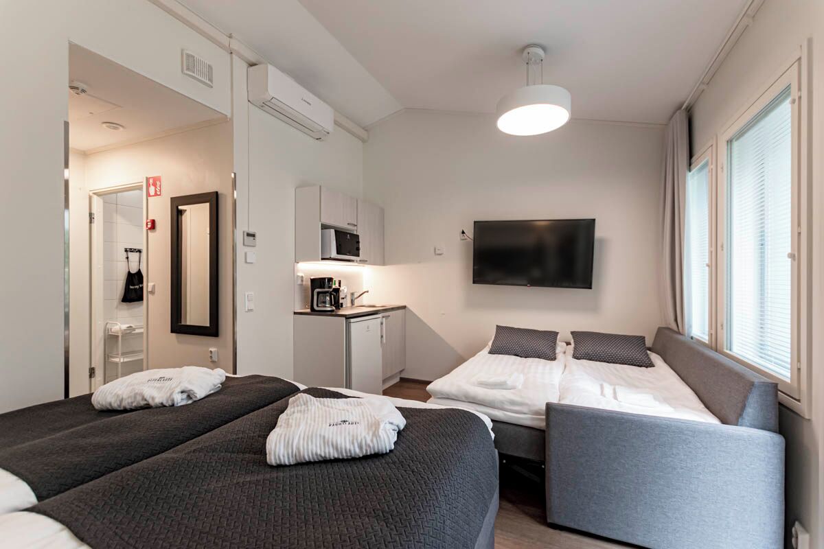 Une chambre d’hôtel avec deux lits, une télévision, un bureau avec un micro-ondes et une salle de bain visible à travers une porte ouverte.