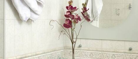 A bathroom with a white sink, a mirror, and two towels hanging on hooks.