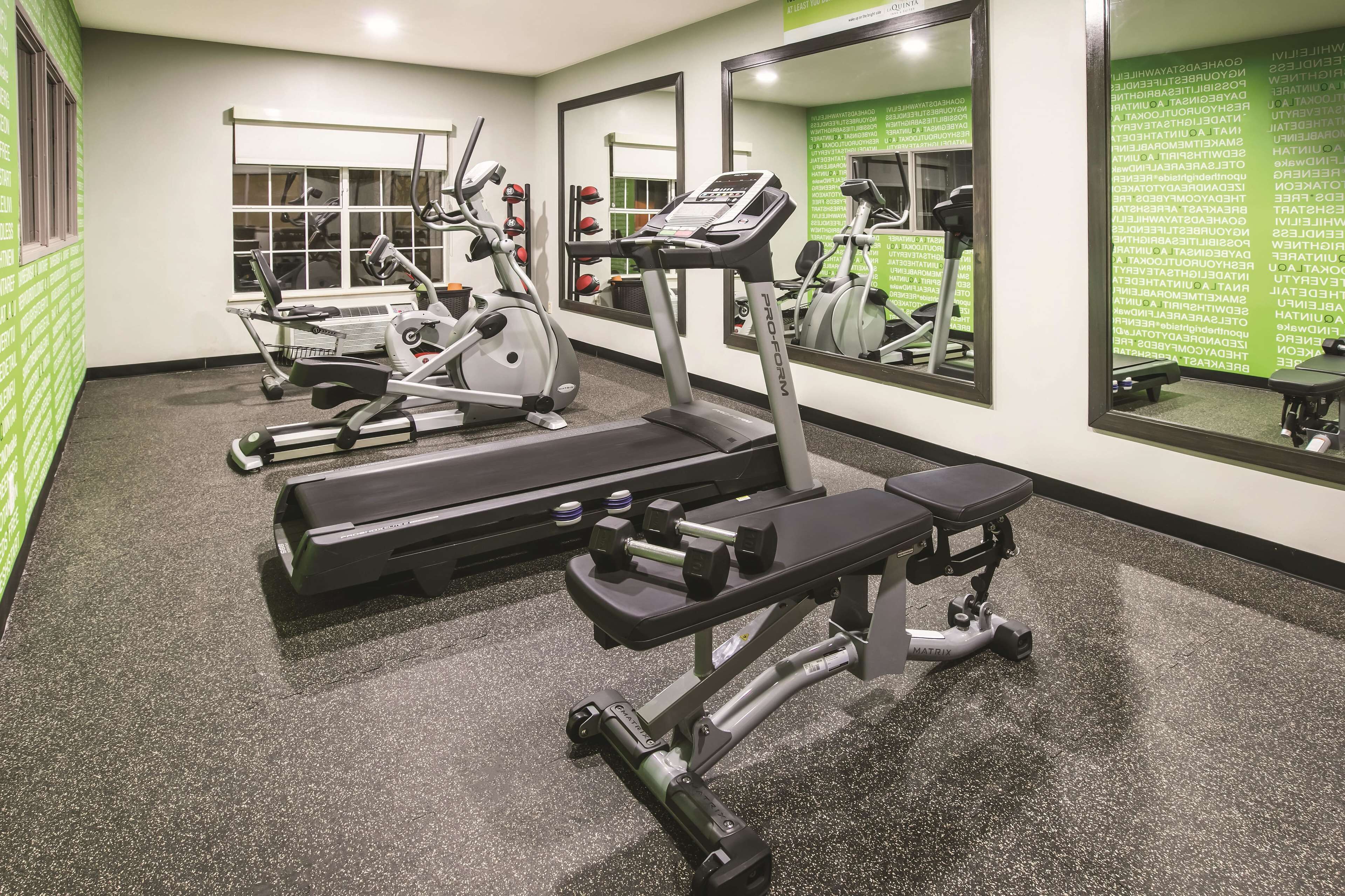 A gym with treadmills, elliptical machines, and weight benches.