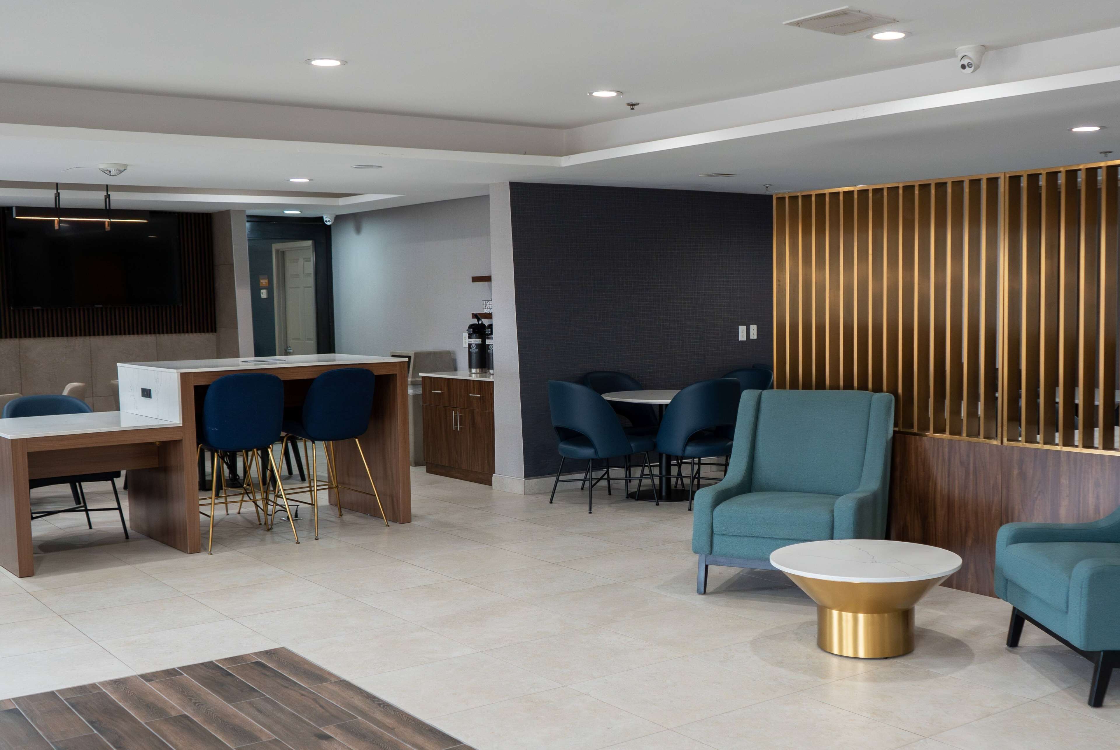 A modern hotel lobby with a reception desk, seating area, and a coffee machine.