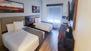 A hotel room with two beds, a TV, a desk, and a window with curtains. - La Quinta Inn & Suites by Wyndham Dallas Mesquite (Mesquite)