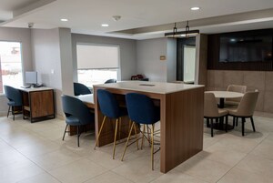 A modern dining area with a central island, blue chairs, and a mix of table styles.