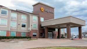 Un hotel con un evidente cartello 'La Quinta', un ingresso coperto e un’area di parcheggio.