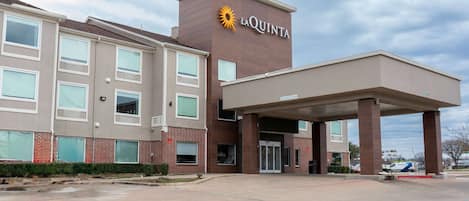 A hotel with a prominent 'La Quinta' sign, a covered entrance, and a parking area.