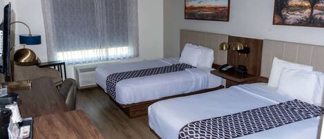 Una habitación de hotel con dos camas, un escritorio, una silla, un televisor y una ventana con cortinas.