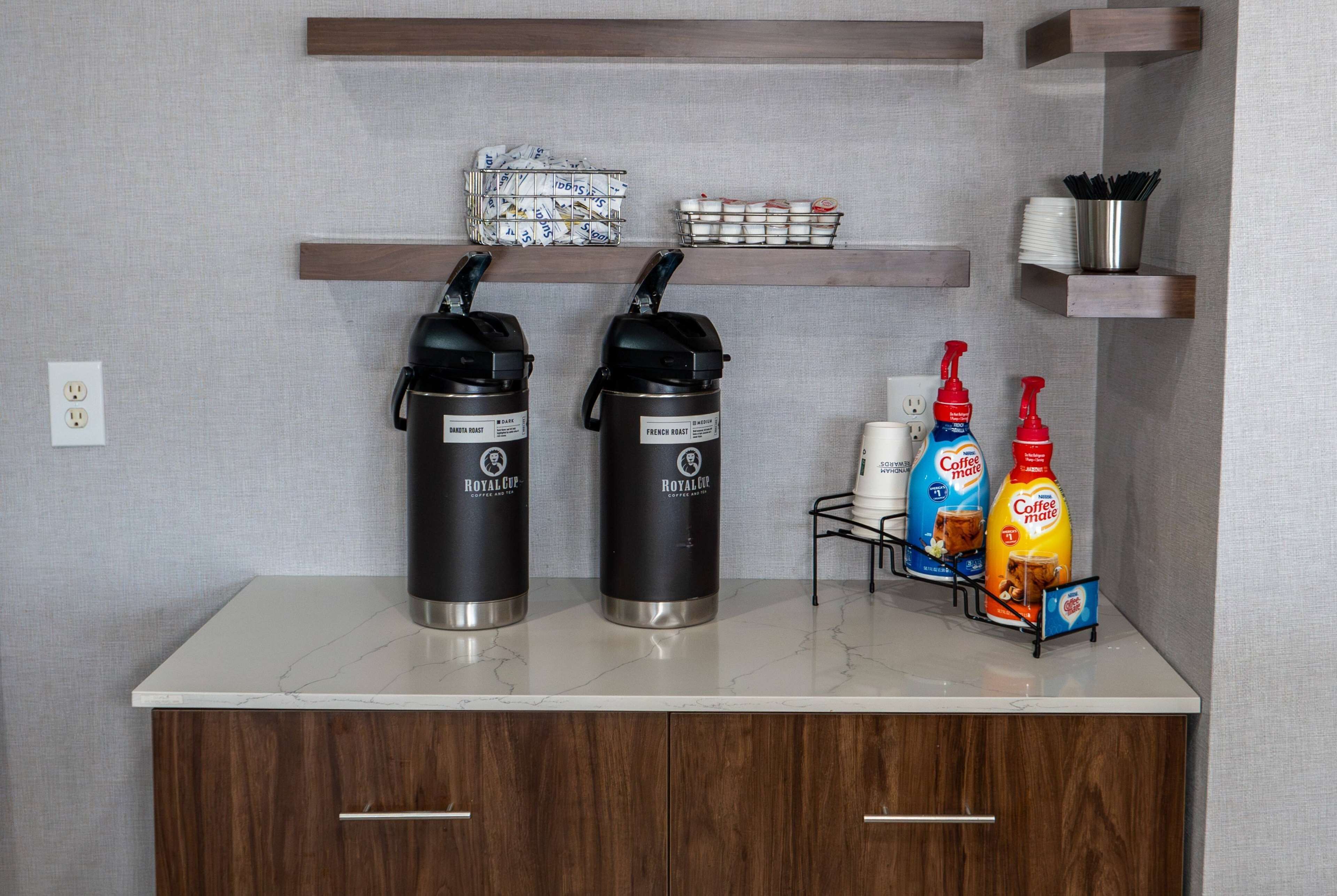 A coffee station with two coffee makers, a coffee machine, and two bottles of coffee creamer.