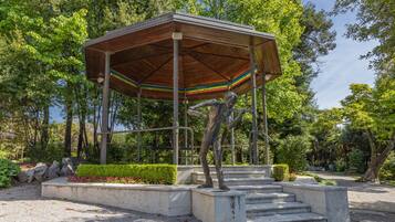 Ein Gazebo mit gestreiftem Dach, umgeben von einem Garten mit Stufen, die hinauf zu ihm führen.