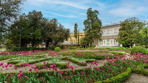 A formal garden with geometrically arranged flower beds and a classical building in the background. - Astoria Hotel Opatija**** (Opatija)