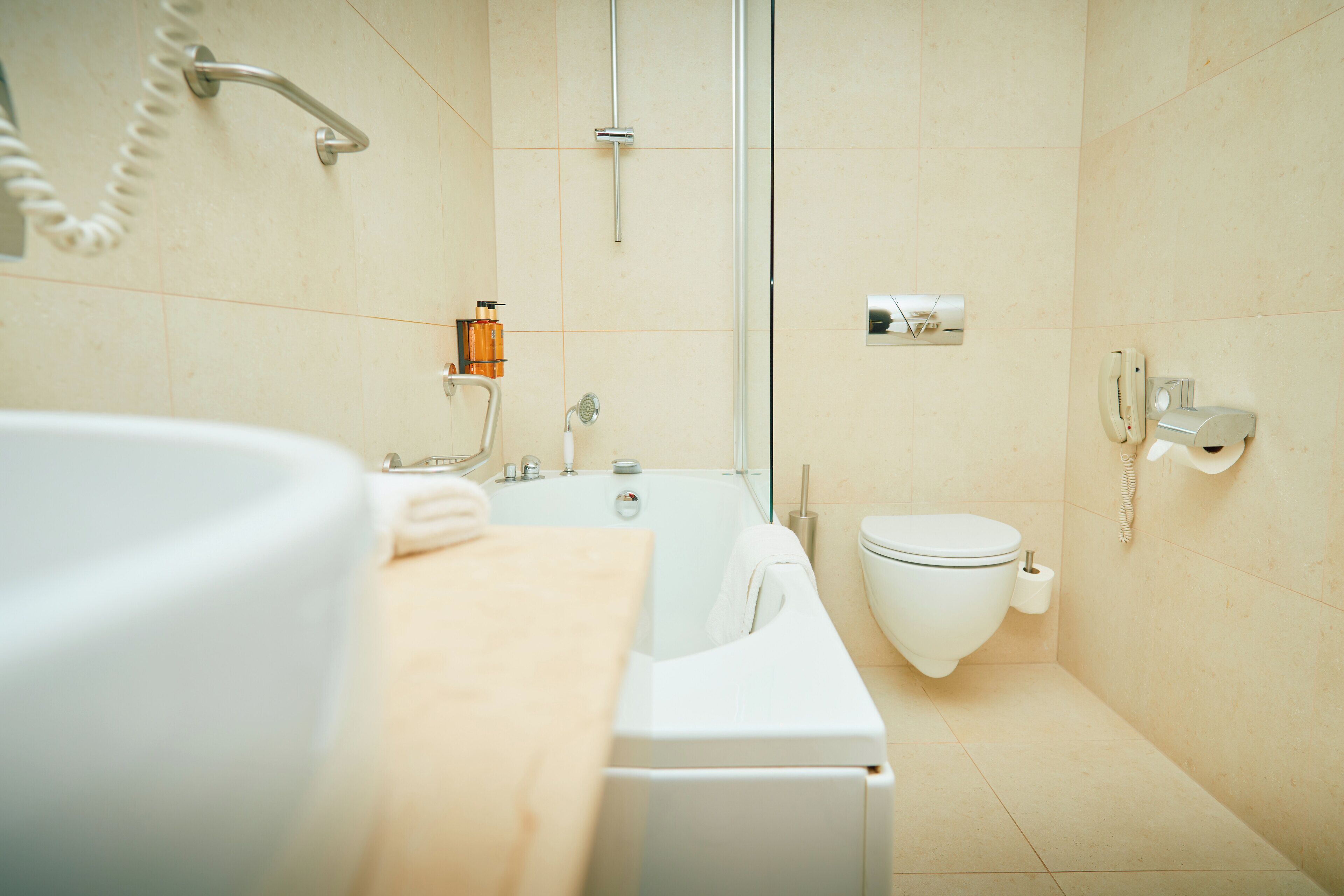 Ein modernes Badezimmer mit Badewanne, Toilette und einem Händetrockner.