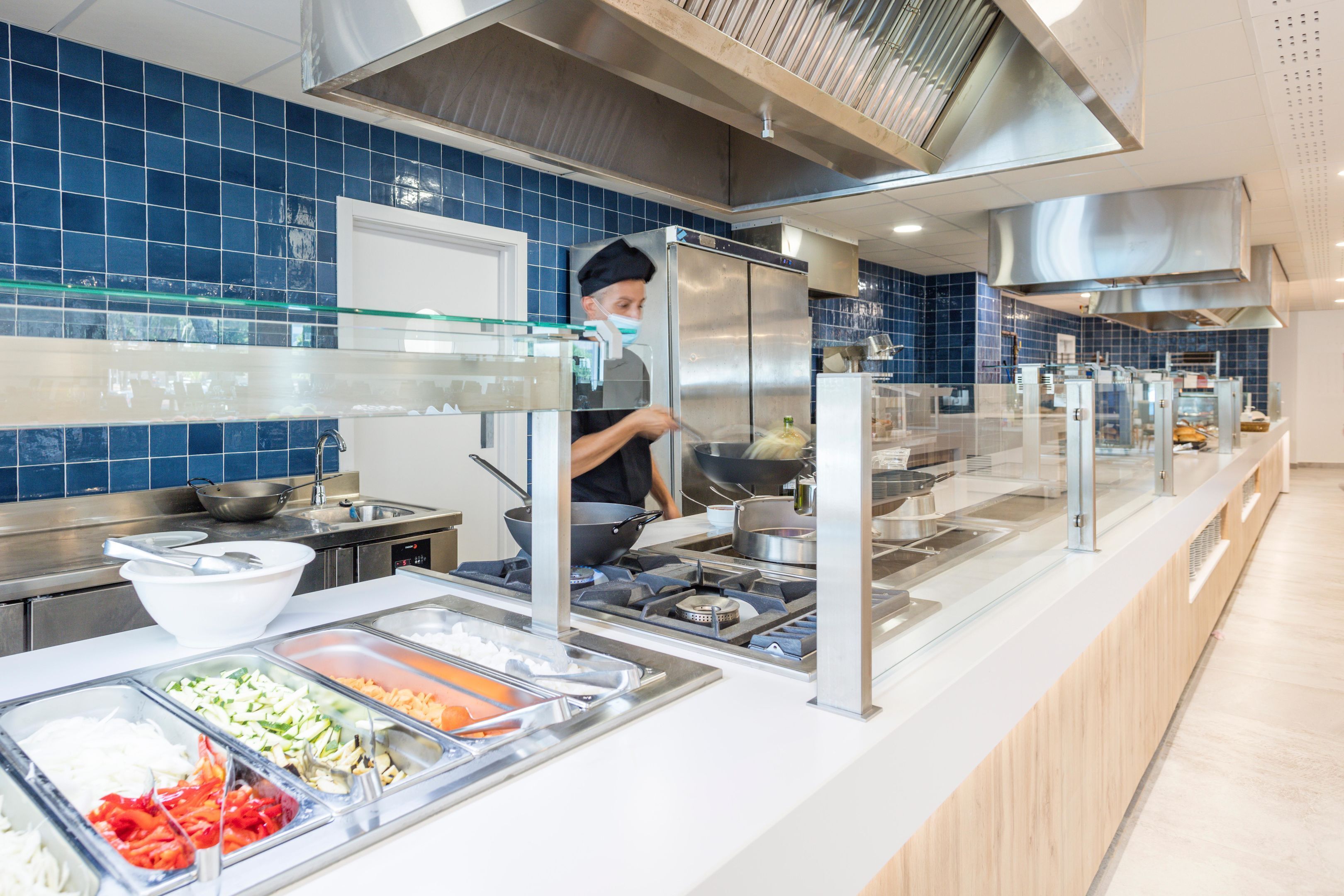 A buffet area with various food stations and a chef preparing food.