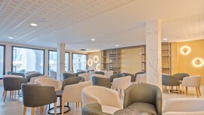Un intérieur moderne doté de plusieurs espaces de détente, de grandes fenêtres et d’un plafond au motif original.