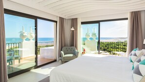 Een ruime slaapkamer met een groot bed, een stoel en uitzicht op de oceaan.