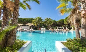 Una piscina azul cristalina rodeada de palmeras y sillas de descanso.