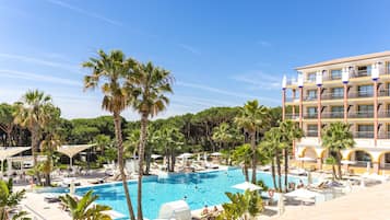 Una piscina techada, una piscina al aire libre, sombrillas