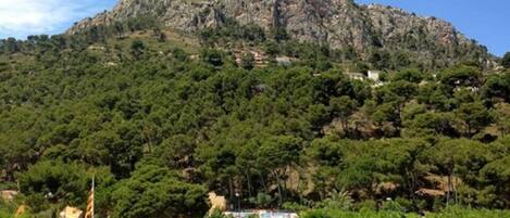 Paisaje montañoso con un asta de banderas y un cartel para un complejo turístico de camping.