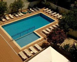 A rectangular swimming pool with a diving board, surrounded by lounge chairs and a small deck area.