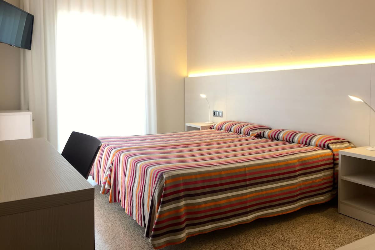 Een hotelkamer met een bed, een bureau en een televisie.