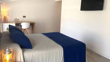 Un dormitorio con cama, escritorio, silla y televisor.
