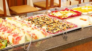 Een buffet met diverse gerechten, waaronder vlees, kazen en salades.