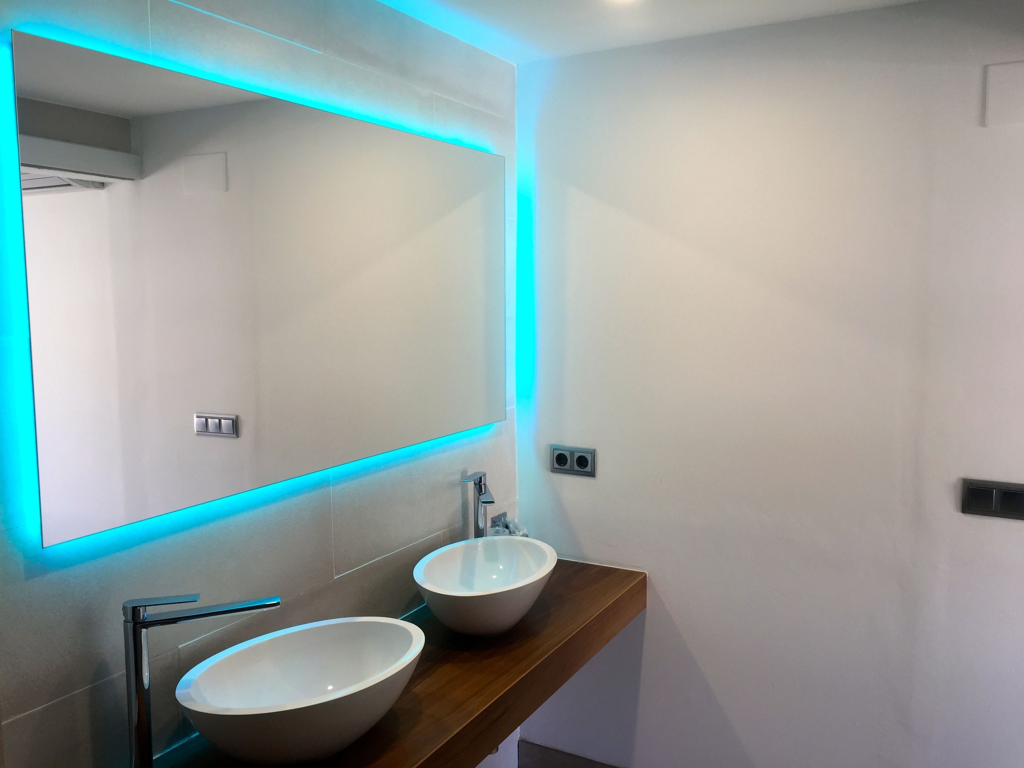 A modern bathroom with a large mirror, two vessel sinks, and a wooden vanity.