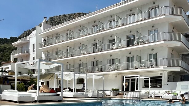 Un hôtel à plusieurs étages doté de balcons, d’une piscine et d’espaces de détente en plein air.