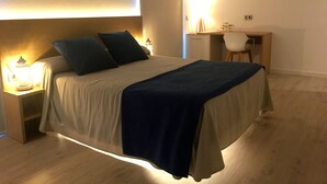 Une chambre à coucher avec un lit, des tables de chevet, un bureau et une chaise.