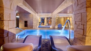 An indoor swimming pool with lounge chairs and a slide. - Hotel Pimar & Spa (Blanes)