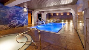 An indoor swimming pool with a stone floor, a glass-enclosed area, and a mural of sea life on the wall. - Hotel Pimar & Spa (Blanes)