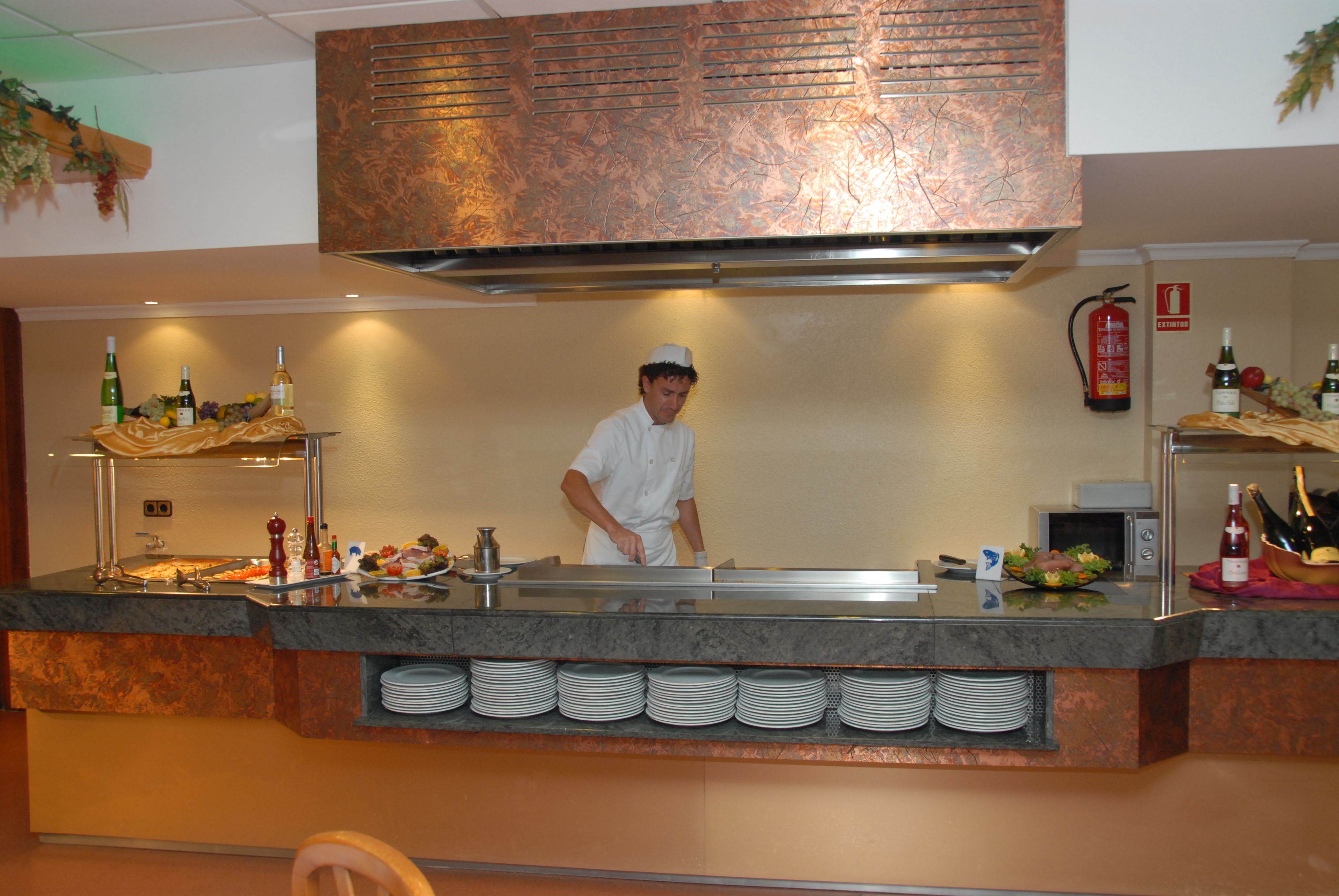Ein Koch an einer Buffetstation mit verschiedenen Speisen und Getränken.