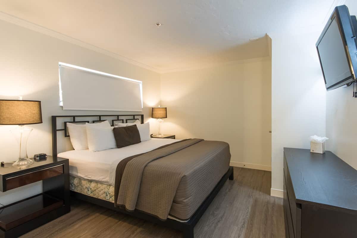 A hotel room with a bed, bedside tables, a TV, and a desk.