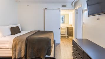 Une chambre à coucher avec un lit, une commode et un téléviseur fixé au mur.