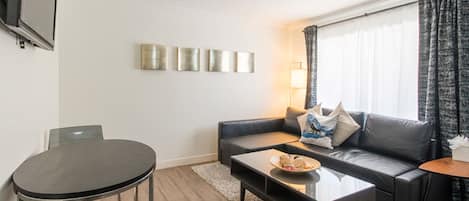 Ein modernes Wohnzimmer mit einer Couch, einem Couchtisch und einem an der Wand befestigten Fernseher.