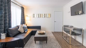 Una sala de estar moderna con un sofá, una mesa de centro y un televisor montado en la pared.