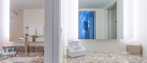 A modern bathroom with a granite countertop, a sink, a mirror, and a towel rack.