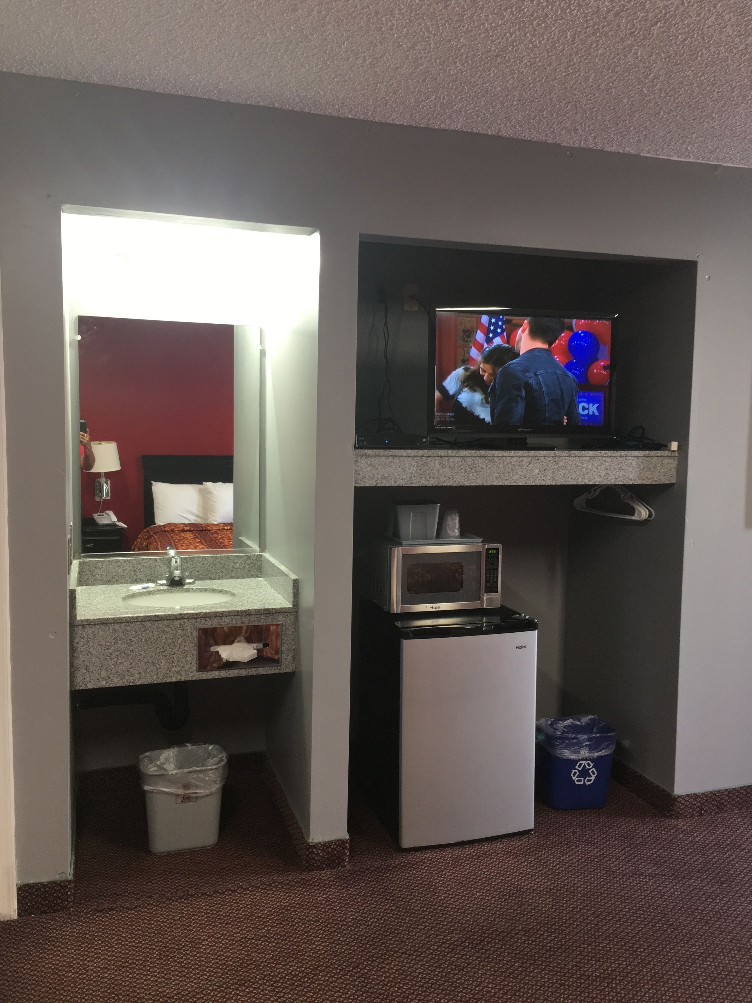 Una habitación de hotel con baño, televisión, microondas y refrigerador.