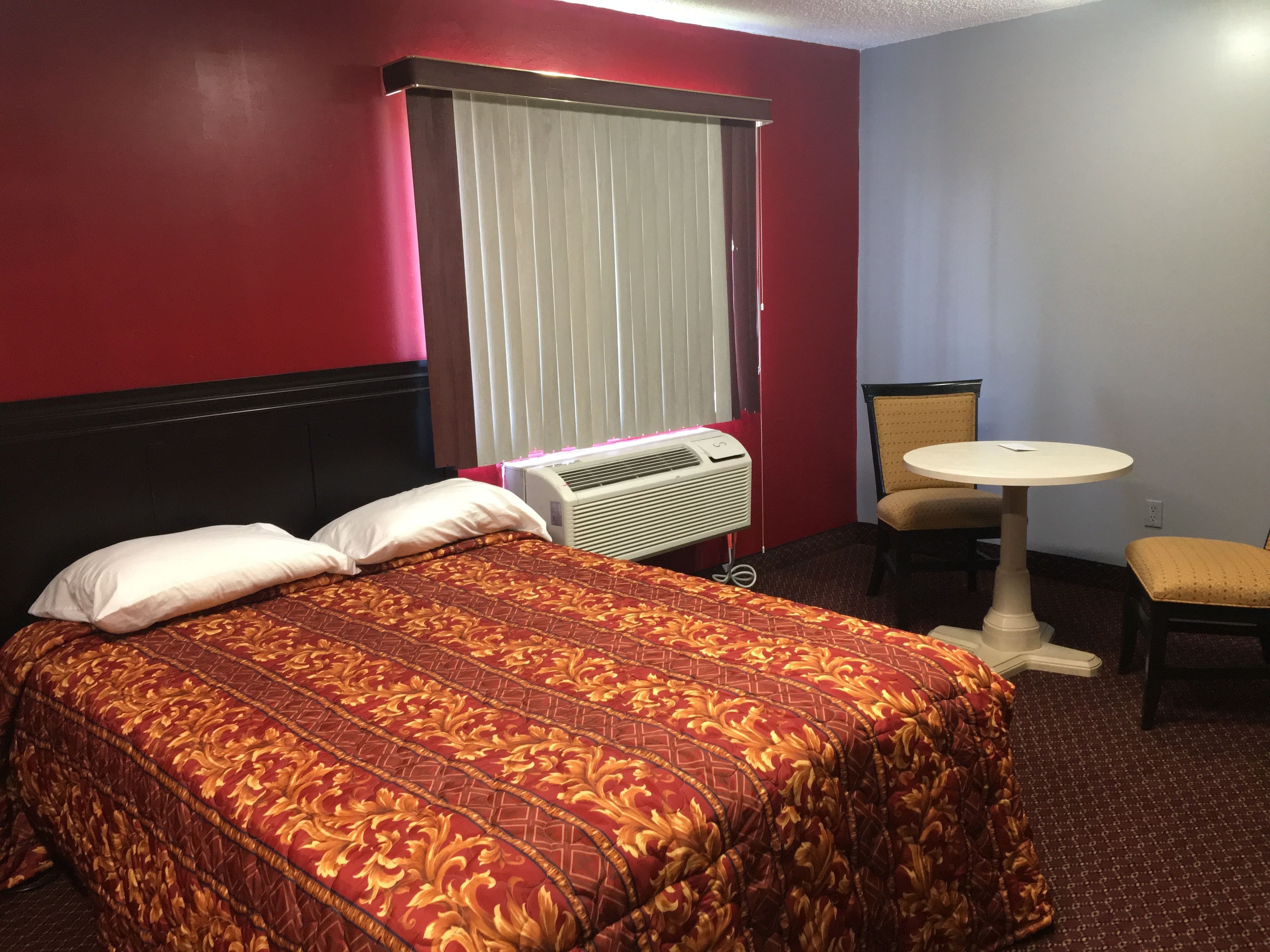 Habitación de hotel con una cama grande, una mesita pequeña y una silla.