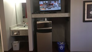Una kitchenette equipada con microondas, un refrigerador pequeño, un lavamanos y un cubo de basura.