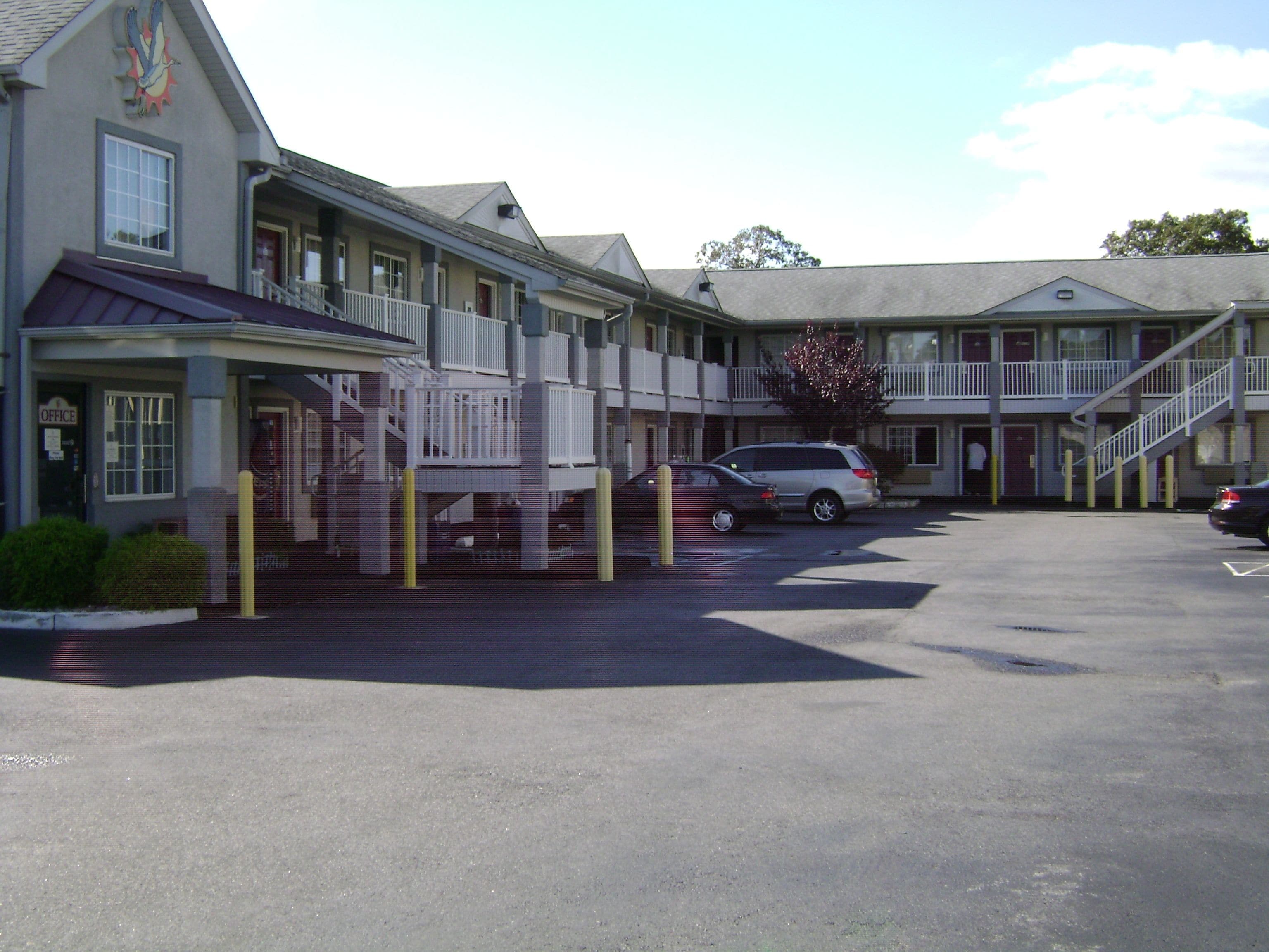 A motel with multiple rooms, a parking lot, and a staircase leading to an upper level.