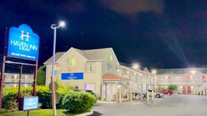 Un hotel de varios pisos con un letrero destacado que dice Haven Inn & Suites, que presenta un diseño moderno con techo plano y varios balcones.