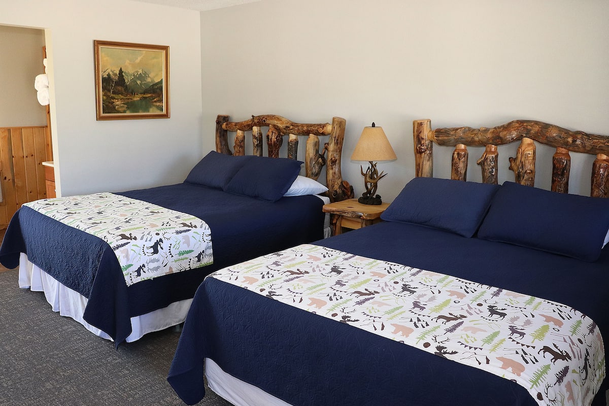 Two twin beds with matching headboards, a bedside table with a lamp, and a painting on the wall.